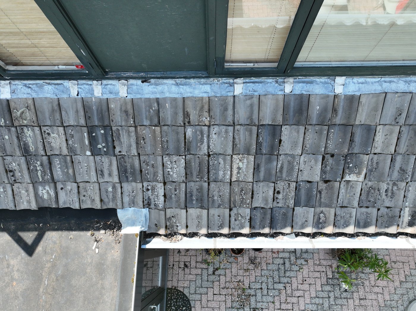 Dronefoto van dakpannen en dakrand bij openslaand raam