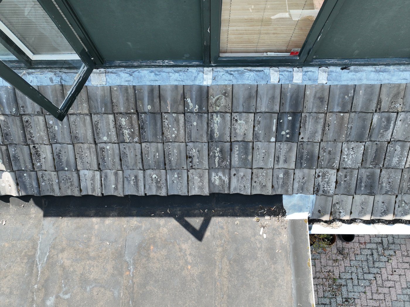 Dronefoto van dakrand en plat dakdeel naast dakpannen